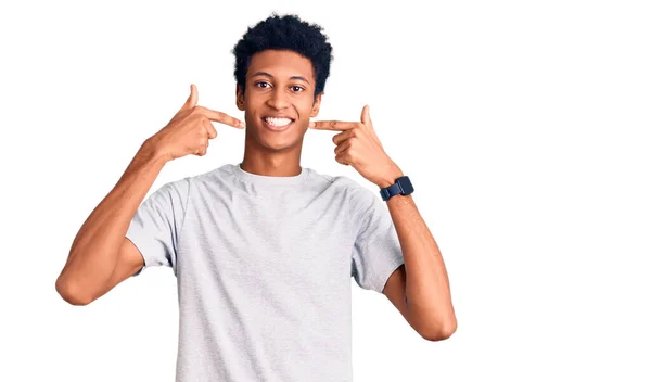 若いアフリカ系アメリカ人の男性は 陽気な笑顔を見せ 指の歯と口で指してカジュアルな服を着ていた 歯の健康の概念 — ストック写真