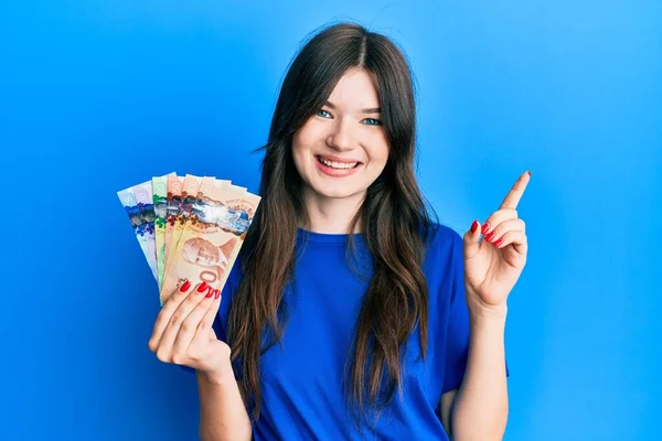 Młody Piękny Kaukaski Dziewczyna Gospodarstwa Kanadyjski Dolary Uśmiechając Szczęśliwy Wskazując — Zdjęcie stockowe