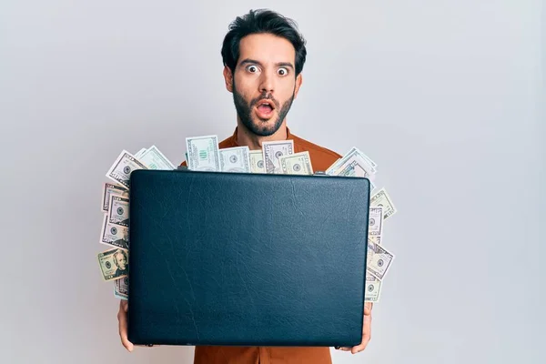 Young Hispanic Man Holding Briefcase Dollars Afraid Shocked Surprise Amazed — Stock Photo, Image