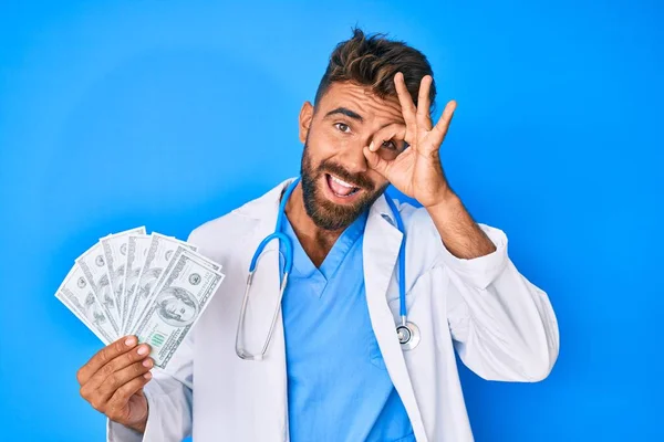 Jonge Spaanse Man Draagt Doktersuniform Houdt Dollars Vast Lachend Blij — Stockfoto