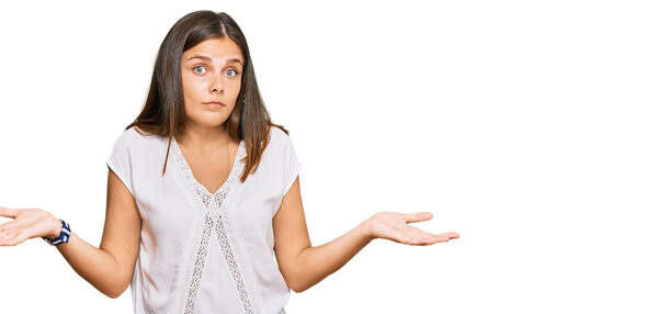 Молодая кавказская женщина, одетая в повседневную одежду, ничего не знает и путает выражение лица с поднятыми руками и руками. Концепция сомнений. 