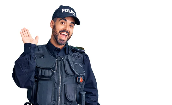 警察の制服を着た若いヒスパニック系の男が挨拶をして手を振っ幸せと笑顔 優しい歓迎ジェスチャー — ストック写真