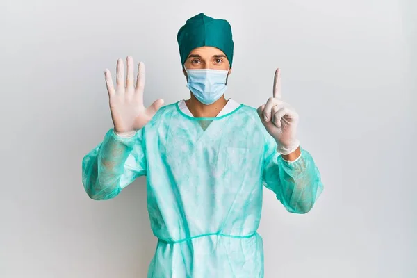 Jovem Homem Bonito Vestindo Uniforme Cirurgião Máscara Médica Mostrando Apontando — Fotografia de Stock