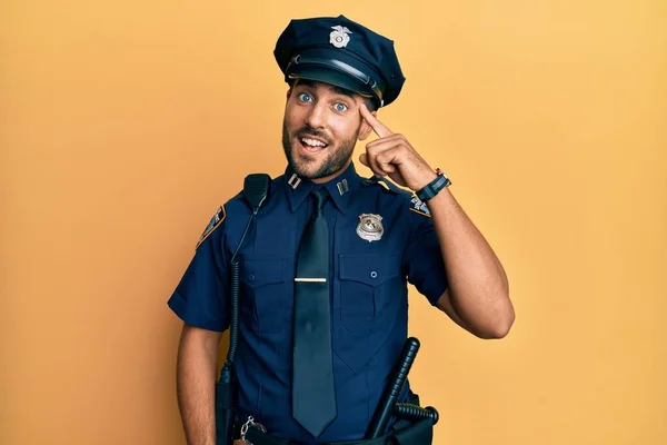 Handsome hispanic man wearing police uniform smiling pointing to head with one finger, great idea or thought, good memory