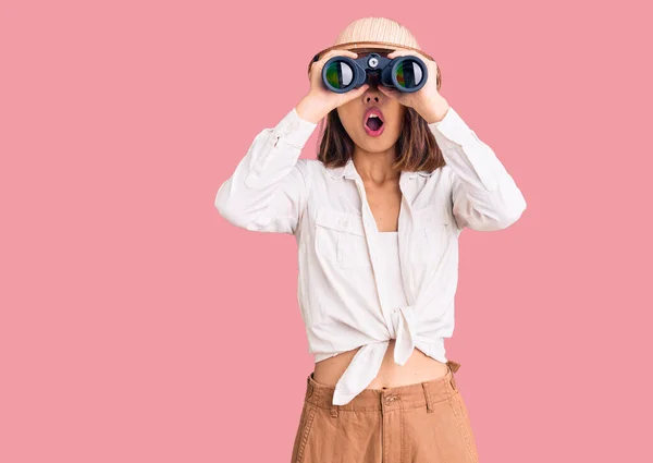 Young Beautiful Chinese Girl Wearing Explorer Hat Holding Binoculars Scared — Stock Photo, Image