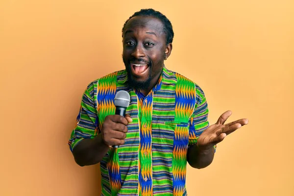 Guapo Joven Negro Cantando Canción Usando Micrófono Celebrando Logro Con —  Fotos de Stock