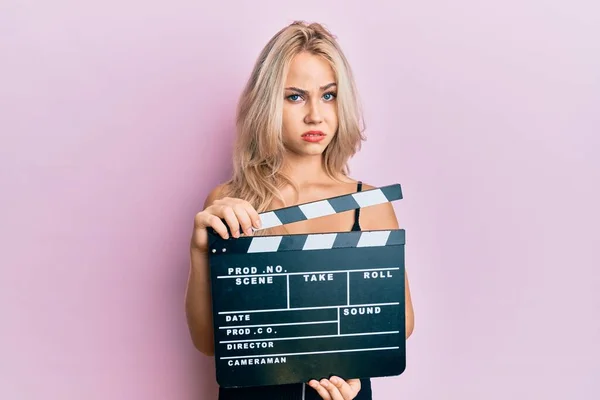 Beautiful Caucasian Blonde Girl Holding Video Film Clapboard Skeptic Nervous — Stock Photo, Image