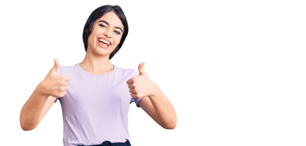 カジュアルな服を着てブルネットのティーンエイジャーの女の子成功サインは手で積極的なジェスチャーを行い 親指を笑顔と幸せ 陽気な表情と勝者のジェスチャー — ストック写真