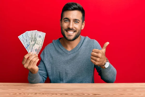 Hombre Hispano Guapo Sosteniendo Dólares Sonriendo Feliz Positivo Pulgar Hacia —  Fotos de Stock