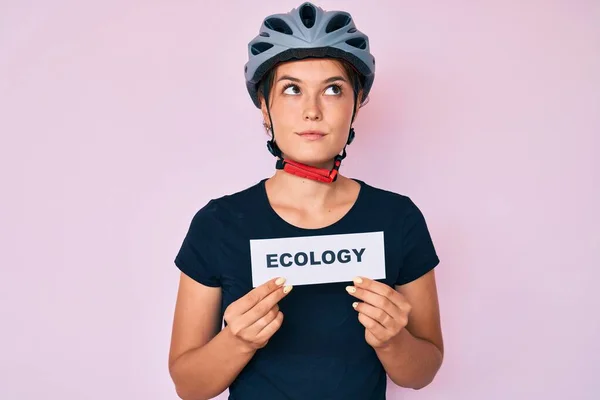 美しい白人女性は自転車のヘルメットを保持します生態学の単語笑顔側を見て離れて考えて見つめて — ストック写真