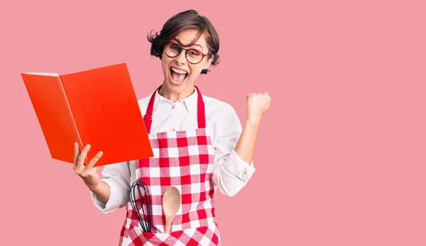 Schöne Junge Frau Mit Kurzen Haaren Trägt Professionelle Bäckerschürze Kochrezeptbuch — Stockfoto