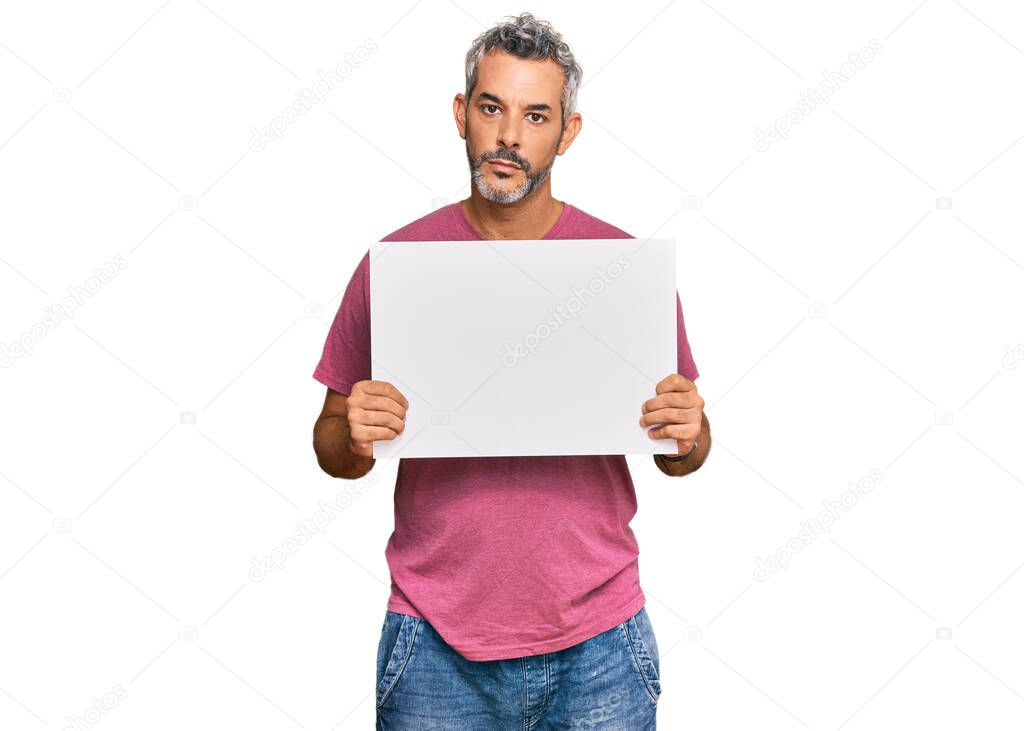 Middle age grey-haired man holding blank empty banner thinking attitude and sober expression looking self confident 
