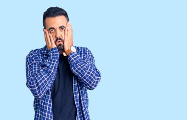 Günlük kıyafetler giyen genç İspanyol adam yorgun eller yüzünü kapatıyor, depresyon ve üzüntü, sorun yüzünden üzgün ve sinirli. 