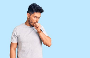 Yakışıklı Latin Amerikalı genç adam, gündelik tişört giyiyor kendini iyi hissetmiyor ve soğuk algınlığı veya bronşitin belirtisi olarak öksürüyor. sağlık hizmeti kavramı. 