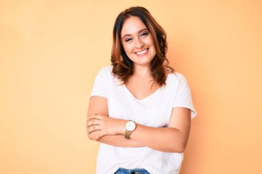 Beyaz günlük tişört giyen, kollarını kavuşturup kameraya gülümseyen beyaz, güzel bir kadın. pozitif kişi. 