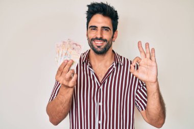 Yakışıklı, sakallı, krallığı elinde tutan yakışıklı adam parmaklarıyla imza atıyor, gülümseyerek mükemmel bir sembol oluşturuyor. 