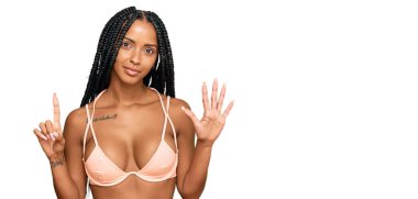 Güzel İspanyol kadın bikini giyiyor ve 6 numaralı parmaklarıyla işaret ederken kendinden emin ve mutlu gülümsüyor.. 