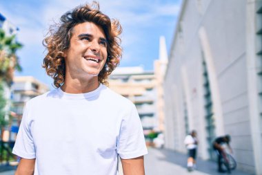 Genç, yakışıklı, gülümseyen bir İspanyol. Şehrin caddesinde mutlu bir şekilde yürüyor.