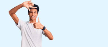 Gündelik kıyafetler giyen, gülümseyen ve mutlu yüzlü elleri ve parmakları olan genç Afro-Amerikan bir adam. yaratıcılık ve fotoğrafçılık kavramı. 