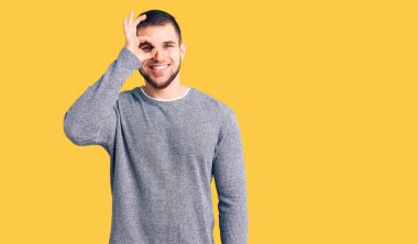 Gündelik kazak giyen genç yakışıklı adam el hareketleriyle gülümsüyor, gözleriyle mutlu yüzlere bakıyor.. 