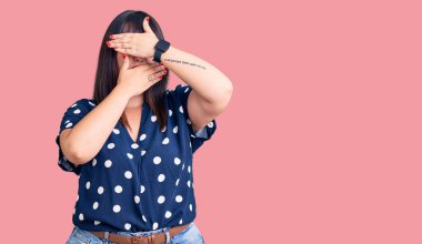 Genç ve cüsseli bir kadın, sıradan kıyafetler giyip gözleri ve ağzı elleriyle kapatıyordu. Şaşırmış ve şok olmuştu. duygu gizleme 