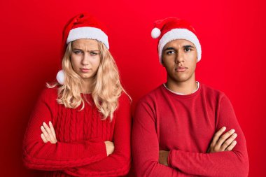 Yılbaşı şapkası takan, kuşkucu ve gergin genç bir çift. Yüzlerinde çapraz kollarla onaylamayan bir ifade var. negatif kişi. 