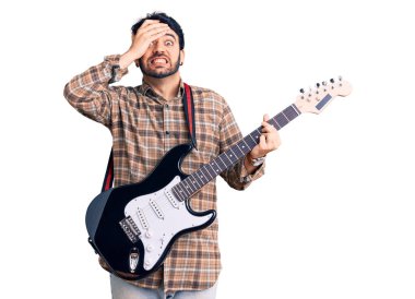 Elektro gitar çalan genç İspanyol adam, gergin ve hayal kırıklığına uğramış, şaşırmış ve sinirli bir yüz ifadesiyle. 