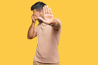 Yakışıklı, günlük kıyafetler giyen, elleriyle gözlerini kapatan, üzgün ve korku ifadeli hareketler yapan İspanyol. utangaç ve olumsuz kavram. 