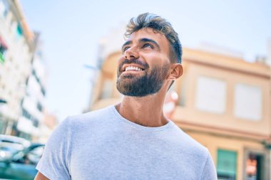 Genç İspanyol adam gülümseyerek şehirde mutlu bir şekilde yürüyor.