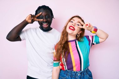 Irklar arası çiftler günlük kıyafetler giyip barış sembolü yapıyorlar. Parmakları yüzlerinde, gülümsüyorlar ve zafer kazanıyorlar. 