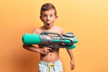 Mayo giyen tatlı sarışın çocuk elinde su tabancası tutuyordu. Korkmuştu ve ağzı açık kalmıştı. 