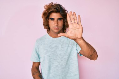 Günlük kıyafetler giyen genç İspanyol adam avucunun içi gibi şarkı söylemeyi kesiyor. Yüzünde olumsuz ve ciddi bir jest olan uyarı ifadesi. 