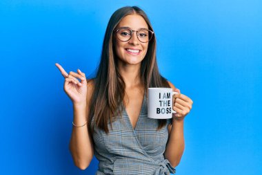 Genç İspanyol kadın patron kahve fincanından içiyor. Gülümsüyor, mutlu bir şekilde elini ve parmağını yana uzatıyordu. 
