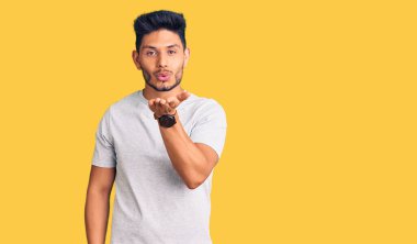 Yakışıklı Latin Amerikalı sıradan tişörtler giyen genç adam kameraya bakıp havada bir öpücük savuruyor ve sevimli ve seksi oluyor. aşk ifadesi. 