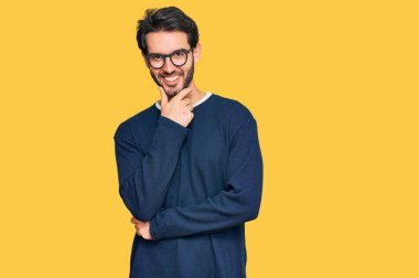 Gündelik giysiler ve gözlük takan genç İspanyol adam kameraya kendinden emin bir şekilde bakıyor kollarını kavuşturup, çenesini kaldırarak gülümsüyor. Olumlu düşünmek. 