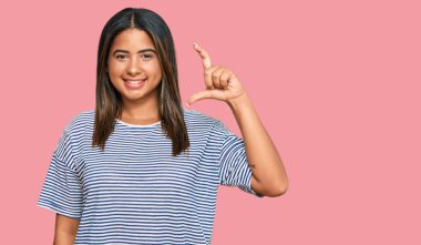 Gündelik kıyafetler giyen, gülümseyen, kendine güvenen, el hareketleriyle hareket eden, parmaklarıyla işaret yapan ve kameraya bakan genç bir Latin kız. ölçüm kavramı. 