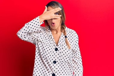 Genç, güzel bir kadın, gündelik elbiseler giymiş, şoka girmiş, yüzünü ve gözlerini eliyle kapatmış, parmaklarından korkuyla bakıyor. 