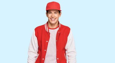 Yüzünde mutlu ve havalı bir gülümseme olan beyzbol üniforması giyen yakışıklı beyaz bir adam. şanslı kişi. 