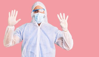 Doktor korumalı Coronavirus üniforması giyen genç İspanyol adam ve tıbbi maske dokuz numarayı gösterip gösterirken kendinden emin ve mutlu gülümsüyor.. 