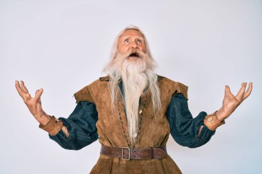 Gri saçlı, uzun sakallı, Viking kostümü giyen yaşlı bir adam. Çılgın deli bağırıyor, agresif bir ifadeyle bağırıyor ve kollarını kaldırıyor. hüsran kavramı. 