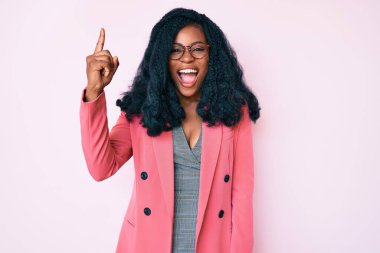 İş ceketi giyen ve gözlüklü güzel bir Afrikalı kadın başarılı bir fikri işaret ediyor. Heyecanlı ve mutlu. Bir numara.. 