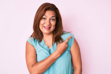 Orta yaşlı esmer, günlük kıyafetler giyen neşeli bir kadın. Yüzünde mutlu ve doğal bir ifadeyle, elleri ve parmaklarıyla yüzünü gösteren bir gülümseme. 