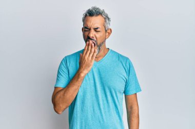 Orta yaşlı, gri saçlı, günlük kıyafetler giyen, esnemekten sıkılmış, ağzı eliyle kapatan bir adam. Huzursuz ve uykulu.. 