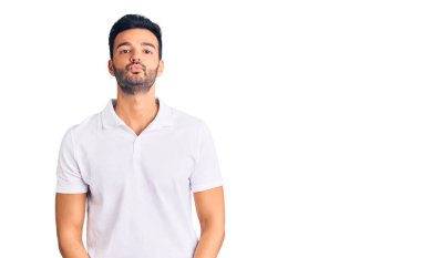 Genç, yakışıklı, sıradan kıyafetler giyen, kameraya bakıp havada öpüşen, güzel ve seksi bir İspanyol. aşk ifadesi. 