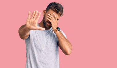 Latin kökenli genç bir adam, günlük kıyafetler giyip, elleriyle gözlerini kapatıyor ve üzgün ve korku ifadeleriyle jestleri durduruyor. utangaç ve olumsuz kavram. 