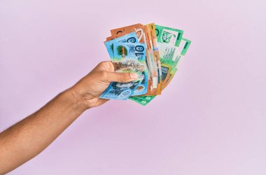 İspanyol el, Avustralya dolarlarını soyutlanmış pembe arka planda tutuyor..