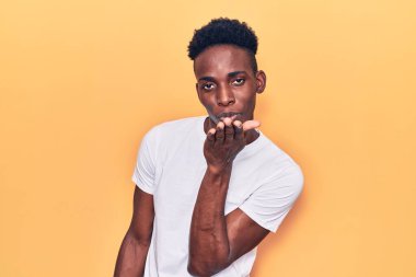 Gündelik giysiler giymiş genç Afro-Amerikan bir adam kameraya bakıp havada el ele öpüşerek sevimli ve seksi oluyor. aşk ifadesi. 