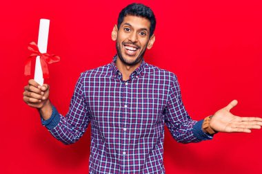 Diplomasını elinde tutan genç Latin adam başarıyı mutlu bir gülümsemeyle ve kazanan yüz ifadesiyle kutluyor. 