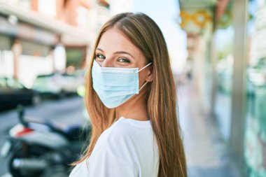 Coronavirus koruma maskesi takan beyaz bir kadın şehirde yürüyor.