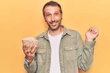 Genç yakışıklı adam elinde nohut kasesi tutarak gururla bağırıyor zaferi ve başarıyı kutluyor. 